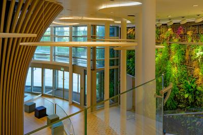 Vue d'une terrasse végétalisée surplombant Paris avec la Tour Eiffel visible à l'horizon sous un ciel bleu.