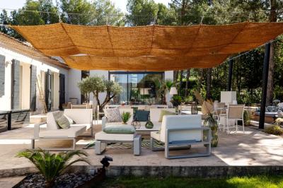 Deux lits simples avec linge blanc, coussins décoratifs, lampes murales et décoration murale en fibres naturelles.