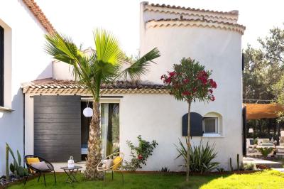 Deux lits simples avec linge blanc, coussins décoratifs, lampes murales et décoration murale en fibres naturelles.