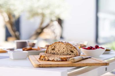 Deux lits simples avec linge blanc, coussins décoratifs, lampes murales et décoration murale en fibres naturelles.