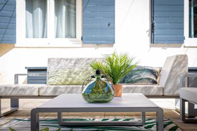 Deux lits simples avec linge blanc, coussins décoratifs, lampes murales et décoration murale en fibres naturelles.