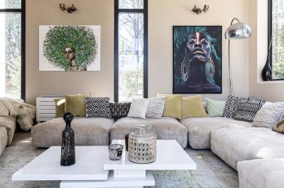 Deux lits simples avec linge blanc, coussins décoratifs, lampes murales et décoration murale en fibres naturelles.