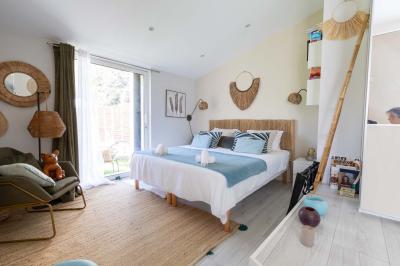 Deux lits simples avec linge blanc, coussins décoratifs, lampes murales et décoration murale en fibres naturelles.