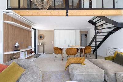 Deux lits simples avec linge blanc, coussins décoratifs, lampes murales et décoration murale en fibres naturelles.