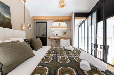 Deux lits simples avec linge blanc, coussins décoratifs, lampes murales et décoration murale en fibres naturelles.