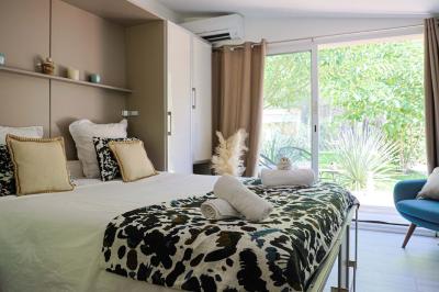 Deux lits simples avec linge blanc, coussins décoratifs, lampes murales et décoration murale en fibres naturelles.