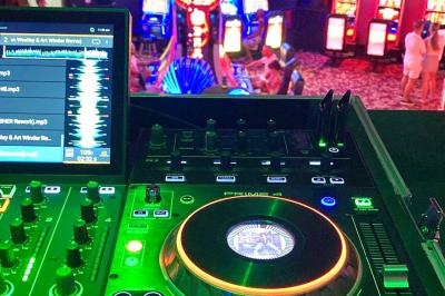 Console de DJ avec enceintes sur une terrasse en hauteur, offrant une vue sur la mer et des bâtiments en arrière-plan.