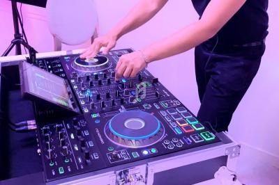 Un DJ mixant de la musique sur une table de mixage lumineuse avec des commandes et des écrans tactiles.