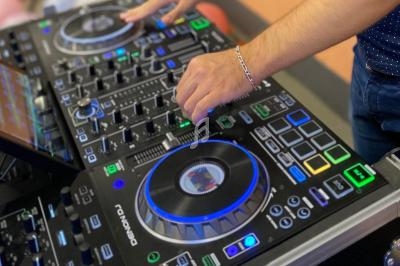 Mains ajustant les commandes d'une table de mixage DJ avec des lumières colorées et des boutons rétroéclairés.