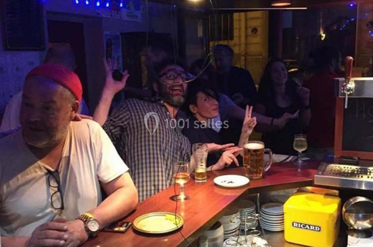 Des personnes discutent et s'amusent autour d'un comptoir de bar avec des boissons posées devant eux.