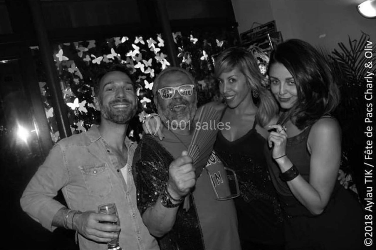 Quatre personnes posent ensemble lors d'une fête, souriantes et détendues, dans un cadre décoré de papillons lumineux.