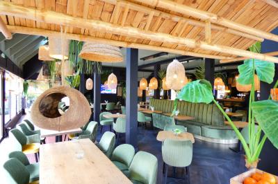 Garage avec sol en béton, mur en parpaings, éclairage au néon, et sortie donnant sur une allée extérieure.