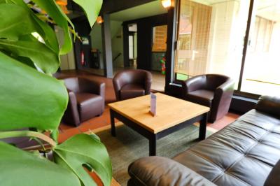 Garage avec sol en béton, mur en parpaings, éclairage au néon, et sortie donnant sur une allée extérieure.