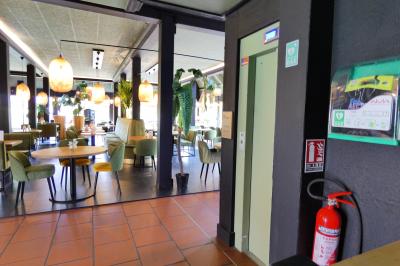 Garage avec sol en béton, mur en parpaings, éclairage au néon, et sortie donnant sur une allée extérieure.