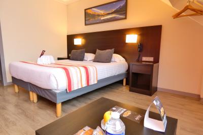 Garage avec sol en béton, mur en parpaings, éclairage au néon, et sortie donnant sur une allée extérieure.