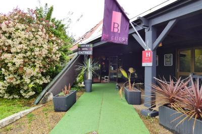 Garage avec sol en béton, mur en parpaings, éclairage au néon, et sortie donnant sur une allée extérieure.
