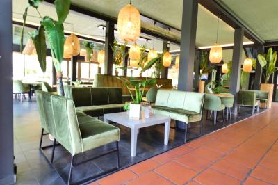 Garage avec sol en béton, mur en parpaings, éclairage au néon, et sortie donnant sur une allée extérieure.