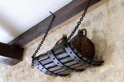 Barbecue en métal rouillé posé sur un socle en pierre, entouré de végétation et de murs en pierre.