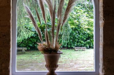 Barbecue en métal rouillé posé sur un socle en pierre, entouré de végétation et de murs en pierre.