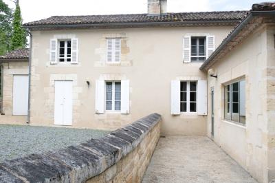 Barbecue en métal rouillé posé sur un socle en pierre, entouré de végétation et de murs en pierre.
