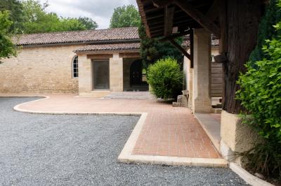 Barbecue en métal rouillé posé sur un socle en pierre, entouré de végétation et de murs en pierre.