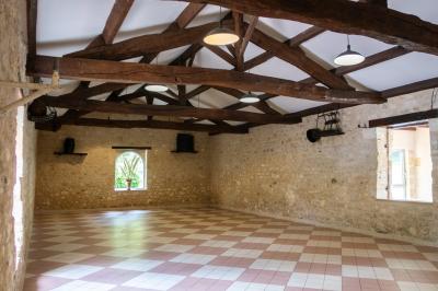 Barbecue en métal rouillé posé sur un socle en pierre, entouré de végétation et de murs en pierre.