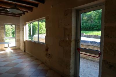 Barbecue en métal rouillé posé sur un socle en pierre, entouré de végétation et de murs en pierre.