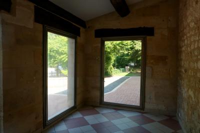 Barbecue en métal rouillé posé sur un socle en pierre, entouré de végétation et de murs en pierre.