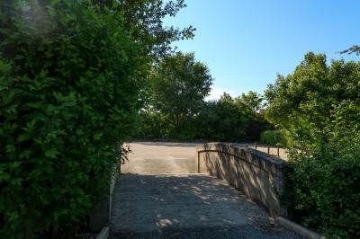 Barbecue en métal rouillé posé sur un socle en pierre, entouré de végétation et de murs en pierre.