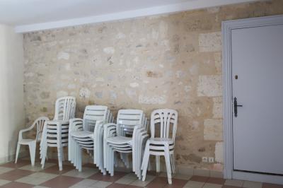 Barbecue en métal rouillé posé sur un socle en pierre, entouré de végétation et de murs en pierre.