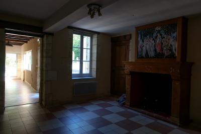 Barbecue en métal rouillé posé sur un socle en pierre, entouré de végétation et de murs en pierre.