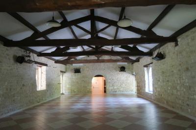 Barbecue en métal rouillé posé sur un socle en pierre, entouré de végétation et de murs en pierre.