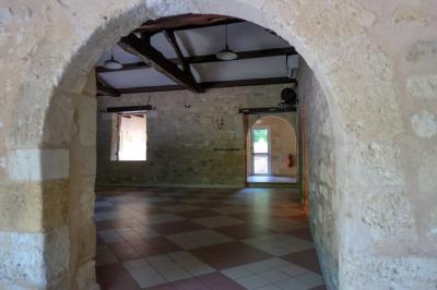 Barbecue en métal rouillé posé sur un socle en pierre, entouré de végétation et de murs en pierre.