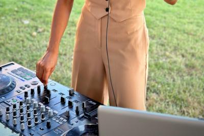 Personne ajustant les commandes d'une table de mixage en plein air, avec de l'herbe en arrière-plan.