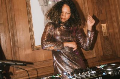 Personne ajustant les commandes d'une table de mixage en plein air, avec de l'herbe en arrière-plan.