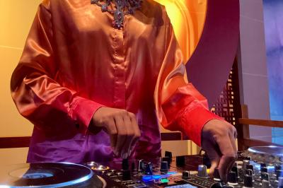 Personne ajustant les commandes d'une table de mixage en plein air, avec de l'herbe en arrière-plan.