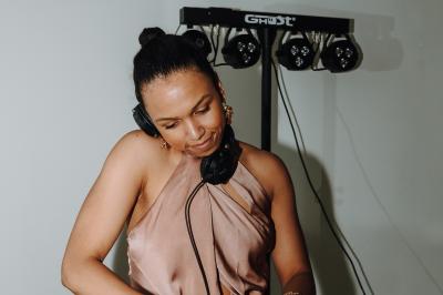 Personne ajustant les commandes d'une table de mixage en plein air, avec de l'herbe en arrière-plan.