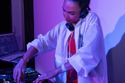 Personne ajustant les commandes d'une table de mixage en plein air, avec de l'herbe en arrière-plan.