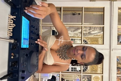 Femme utilisant une table de mixage dans une salle élégante avec des miroirs et des ornements dorés en arrière-plan.