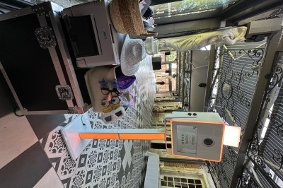 Borne photo avec accessoires festifs sur un sol à motifs, dans un espace lumineux avec grandes baies vitrées.