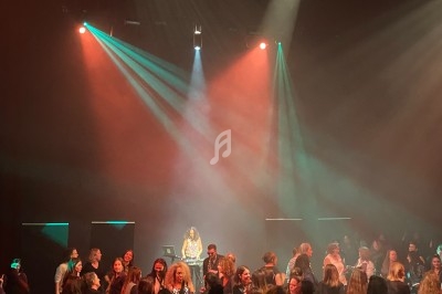 Groupe de personnes dans une salle sombre, éclairée par des projecteurs colorés, semblant participer à un événement festif.