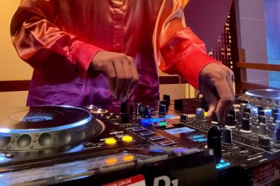 Une DJ mixant de la musique sur une table de mixage dans une ambiance lumineuse violette.