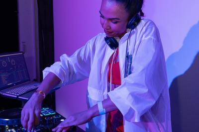 Une DJ mixant de la musique sur une table de mixage dans une ambiance lumineuse violette.