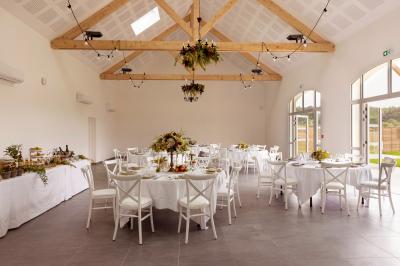 Table dressée en extérieur avec des plats, ustensiles de cuisine et présentoirs en bois devant une haie verte.