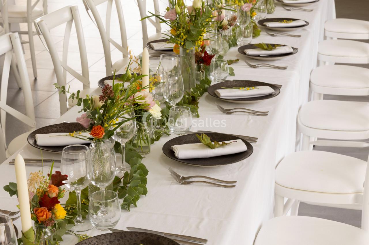 Table dressée avec une nappe blanche, vaisselle élégante, serviettes pliées et décorations florales colorées.