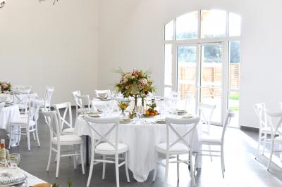 Table dressée en extérieur avec des plats, ustensiles de cuisine et présentoirs en bois devant une haie verte.