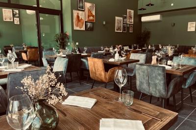 Table dressée en extérieur avec des plats, ustensiles de cuisine et présentoirs en bois devant une haie verte.