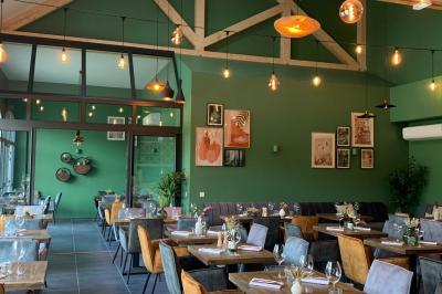 Table dressée en extérieur avec des plats, ustensiles de cuisine et présentoirs en bois devant une haie verte.