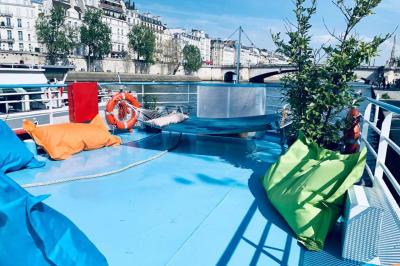 Intérieur d'une péniche avec parquet, bar en bois, tapis décoratif et grandes fenêtres donnant sur l'eau.