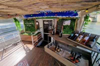 Intérieur d'une péniche avec parquet, bar en bois, tapis décoratif et grandes fenêtres donnant sur l'eau.